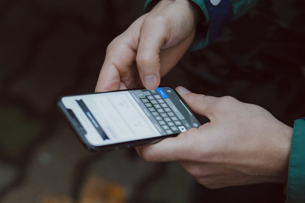 両手でスマートフォンを持ち文字を入力する手元