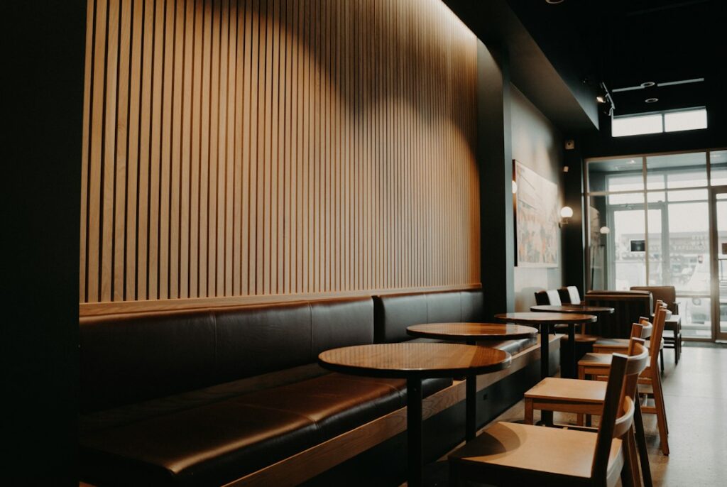 丸いテーブルと椅子、壁沿いのベンチが並ぶカフェの店内