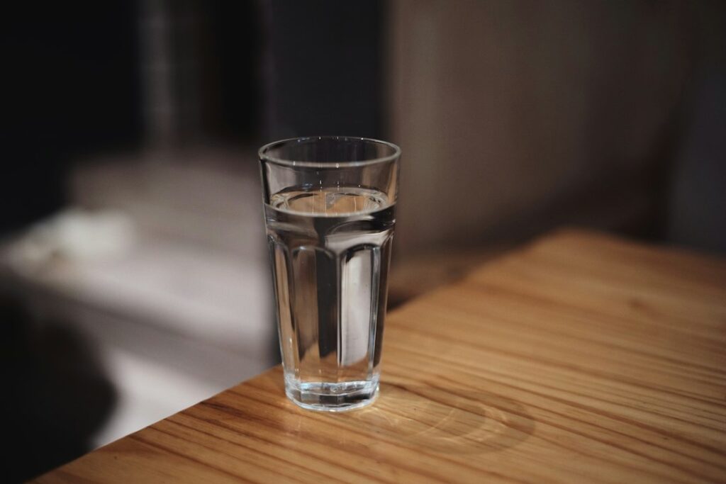 木のテーブルに置かれた水の入った透明なグラス