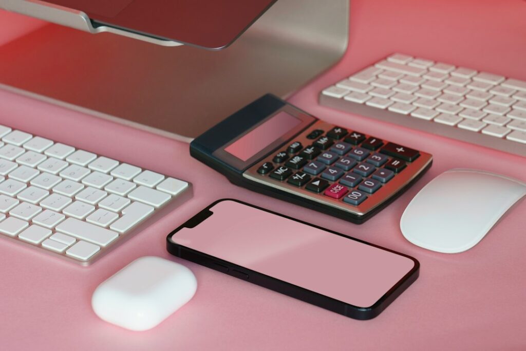 机に置かれた電卓とスマートフォン（予算管理のイメージ）